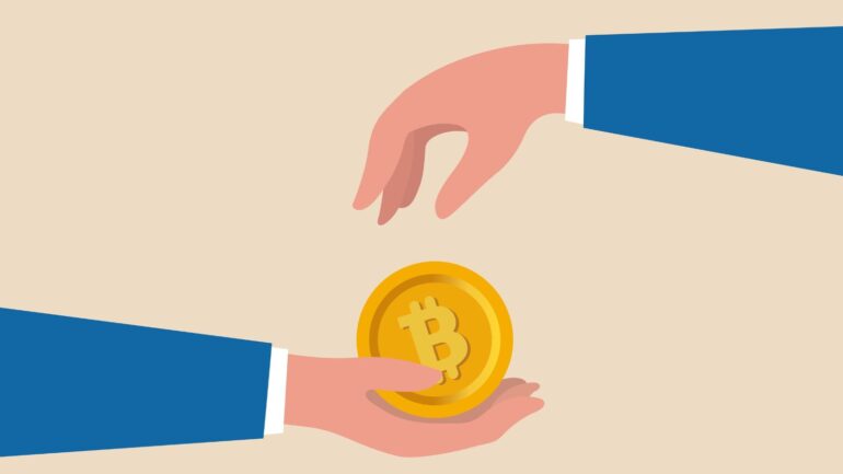 Handen met een bitcoinmunt.