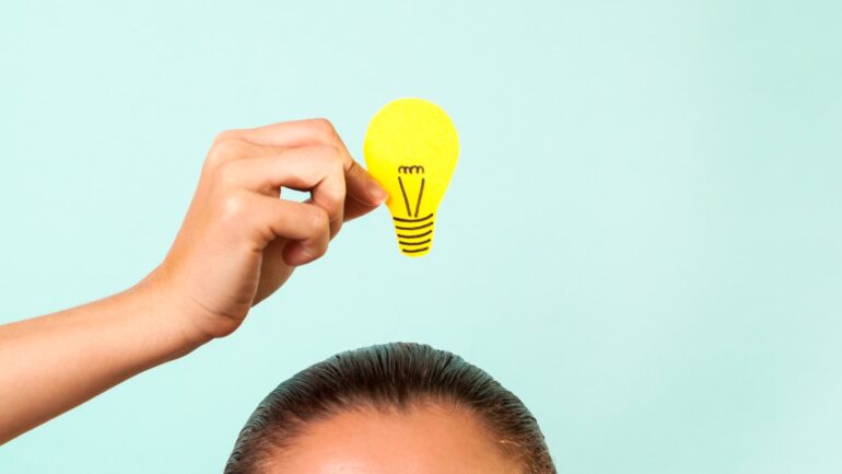 Persoon houdt gloeilamp boven hoofd ter illustratie van marketeers die slimmer moeten werken met AI