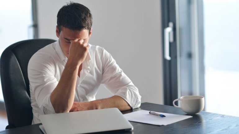 Man die gefrustreerd achter de laptop zit