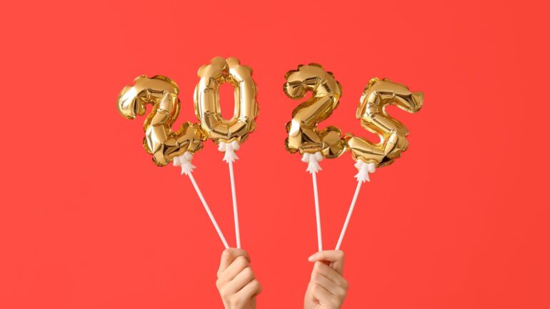 vrouwelijke handen met 2025 ballonnen op een stokje.