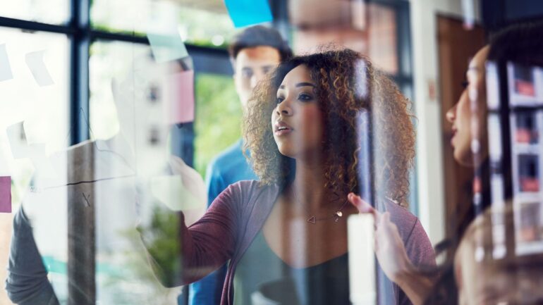 Collega's bij glazen want met post-its die met reflectievragen de positionering van de organisatie bepalen