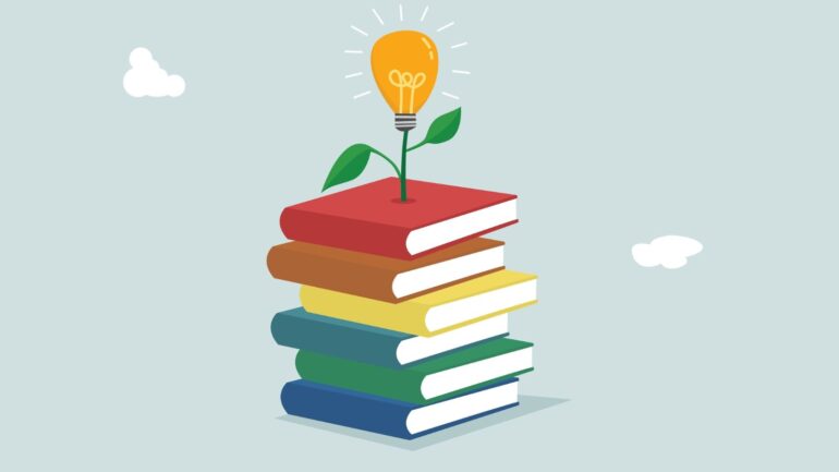 Gekleurde boeken met een lampje bovenop.