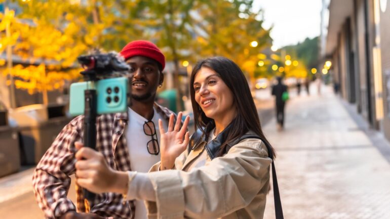 2 personen die in een stad social media-content filmen ter illustratie van zichtbaar blijven als gemeente op social media
