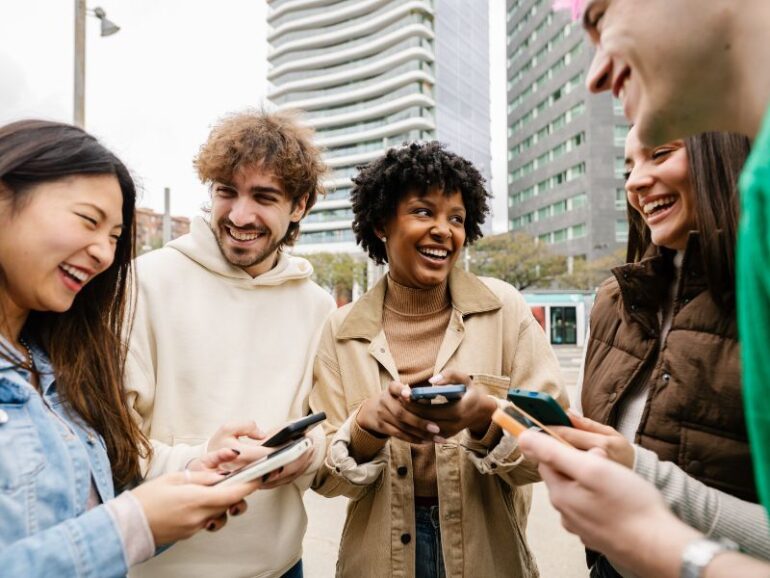 Een groep lachende jongeren met telefoons. 