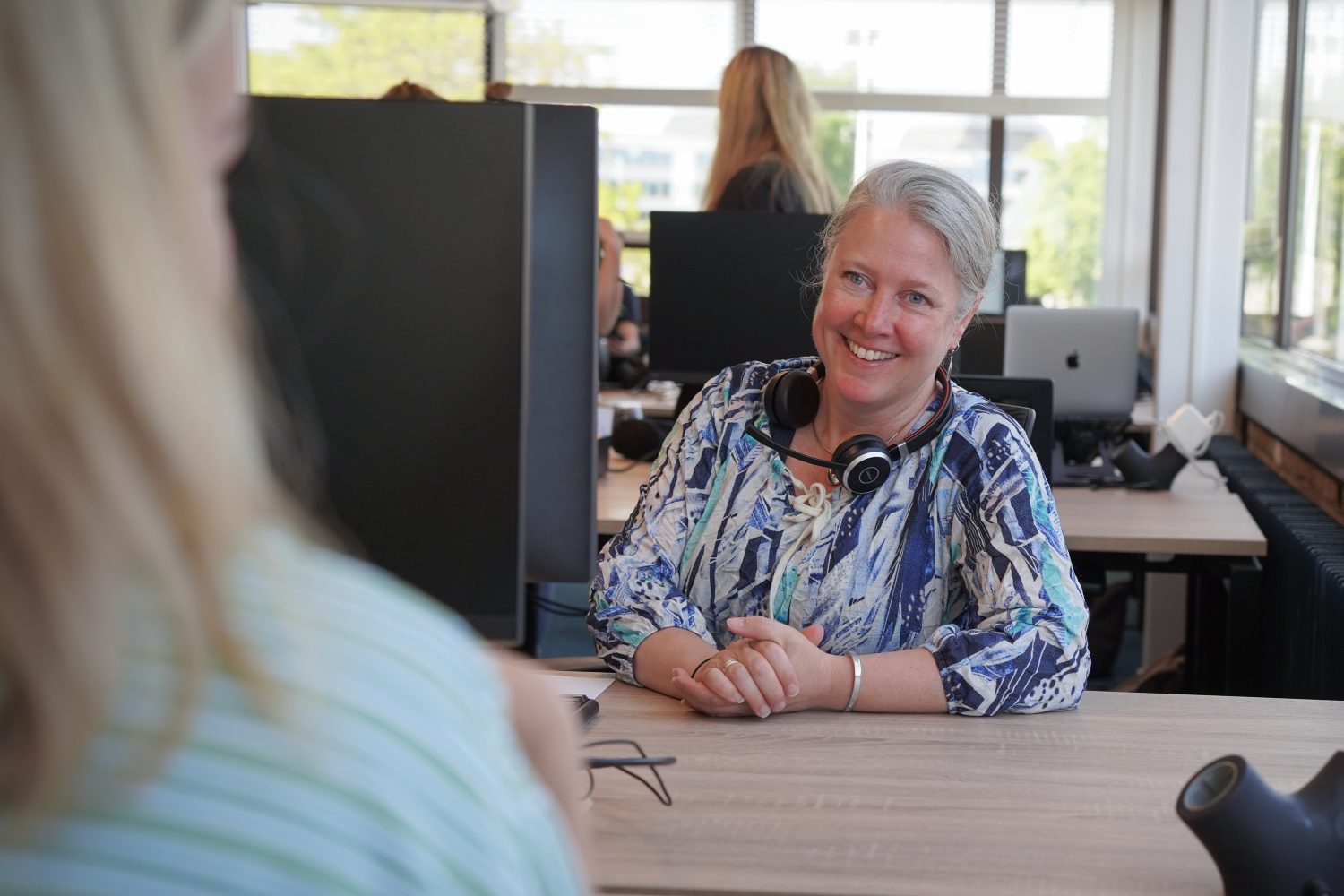 Collega Christa Verwey glimlacht naar een collega tegenover haar.