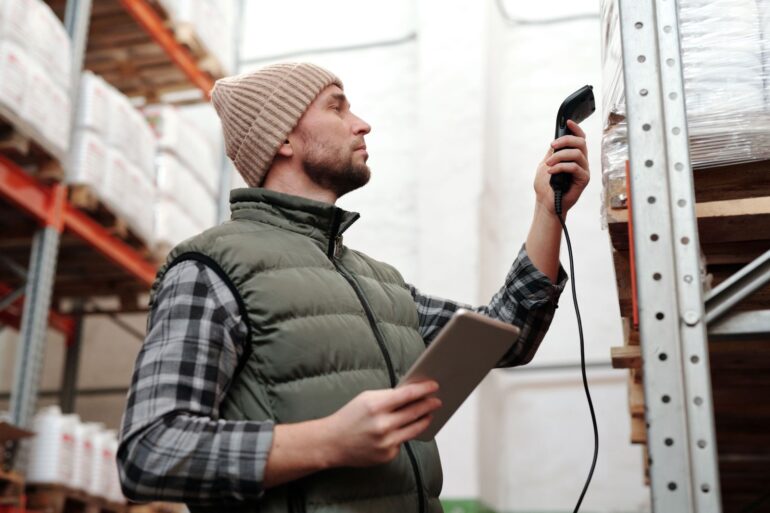 Magazijnmedewerker scant voorraad met handheld scanner en tablet