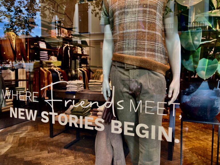 Etalage van een kledingwinkel met de tekst 'Where friends meet, new stories begin.'