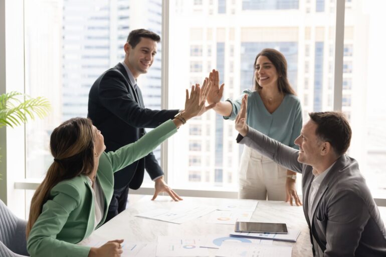 Vier medewerkers van een bedrijf geven elkaar een high five, omdat ze samen een probleem hebben opgelost.