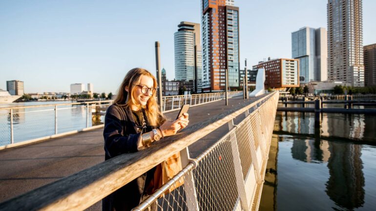 Vrouw met telefoon op brug in Rotterdam