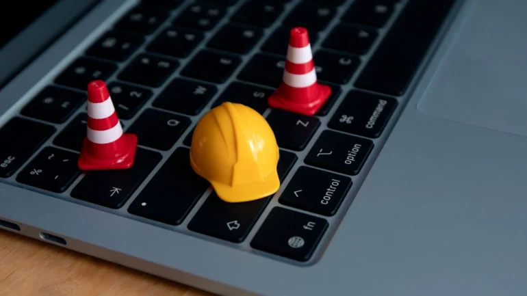 Laptop met werkhelm en verkeerskegels